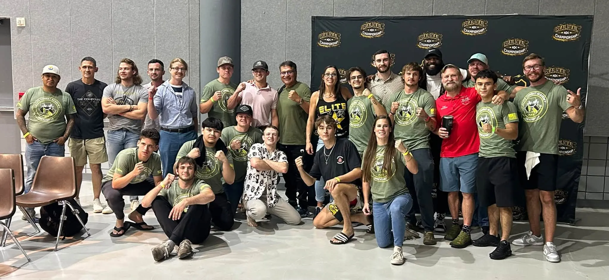 The Elite Combat Academy team in matching green shirts in front of a Real Deal Championship backdrop